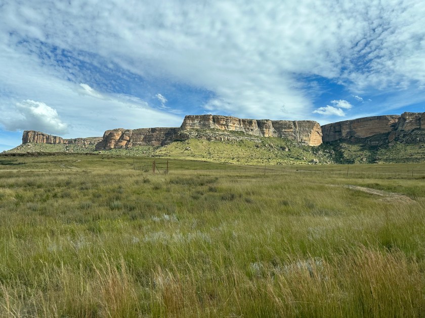 Dynasty Red Mountain: grasveld, tafelbergen en wolken in blauwe lucht. 