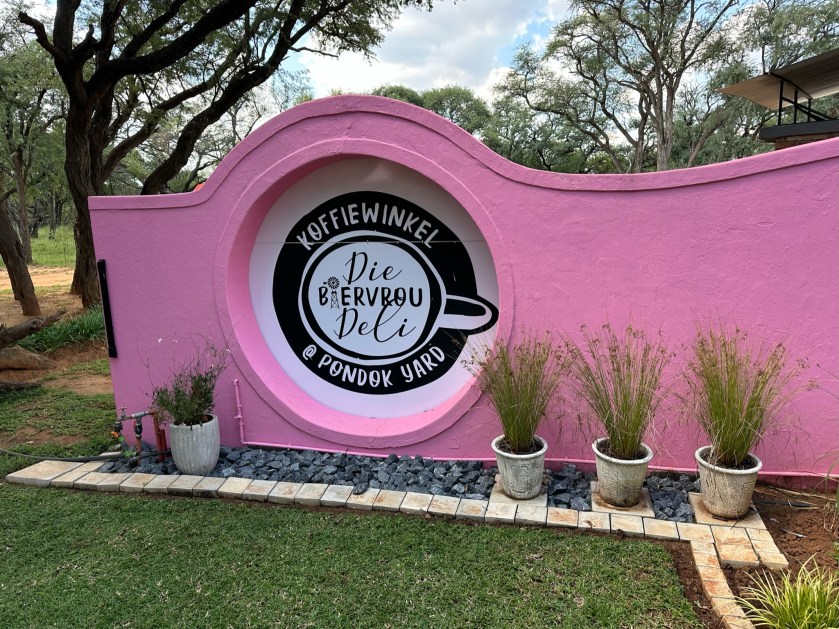 Die Boervouw Deli logo op roze muur.