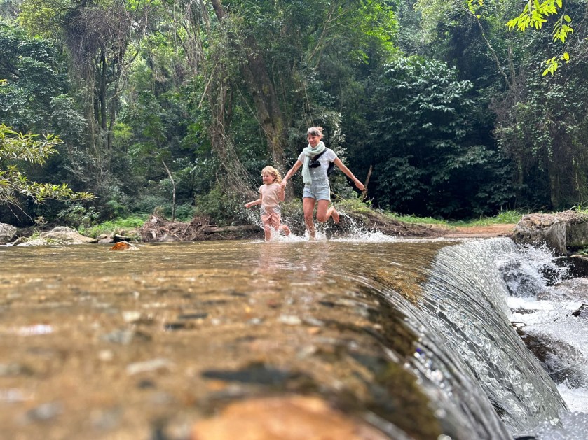 Debengeni Falls: toeriste met kind holt door rivier. 