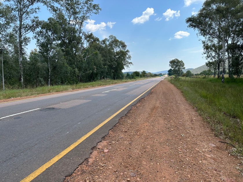 Polokwane Freeway:: kaarsrechte weg tussen bomen. 