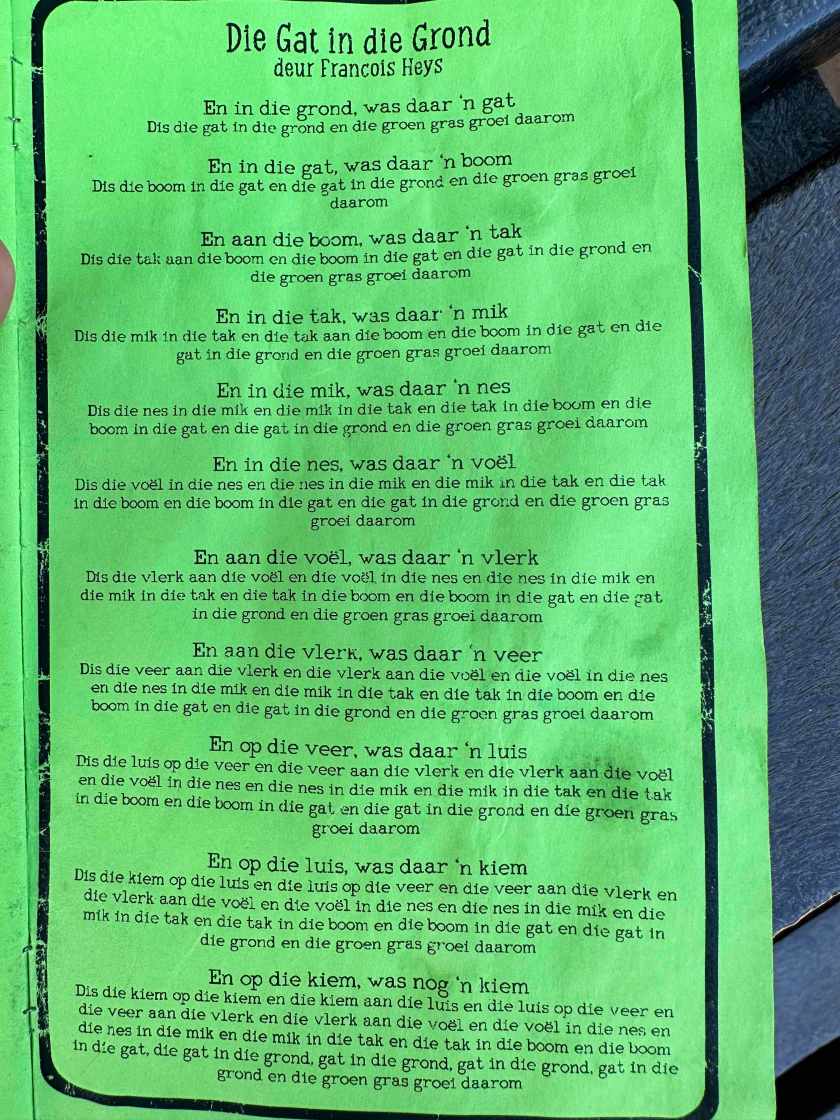 Die gat in die Grond; groene affiche met de tekst van het kinderliedje. 