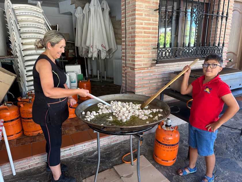 Villanueva de la Concepción: vrouw en jongen roeren kippenblokjes en olie in grote paellapan.