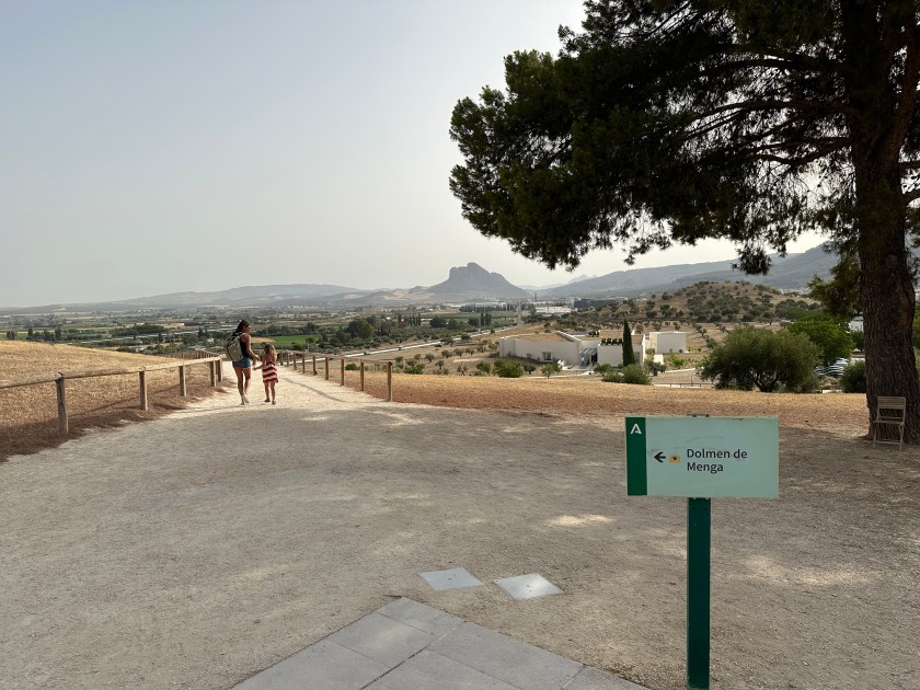 Dolmen van Antequerra: verharde witte toegangsweg met “Rots der verliefden” in verre achtergrond. 
