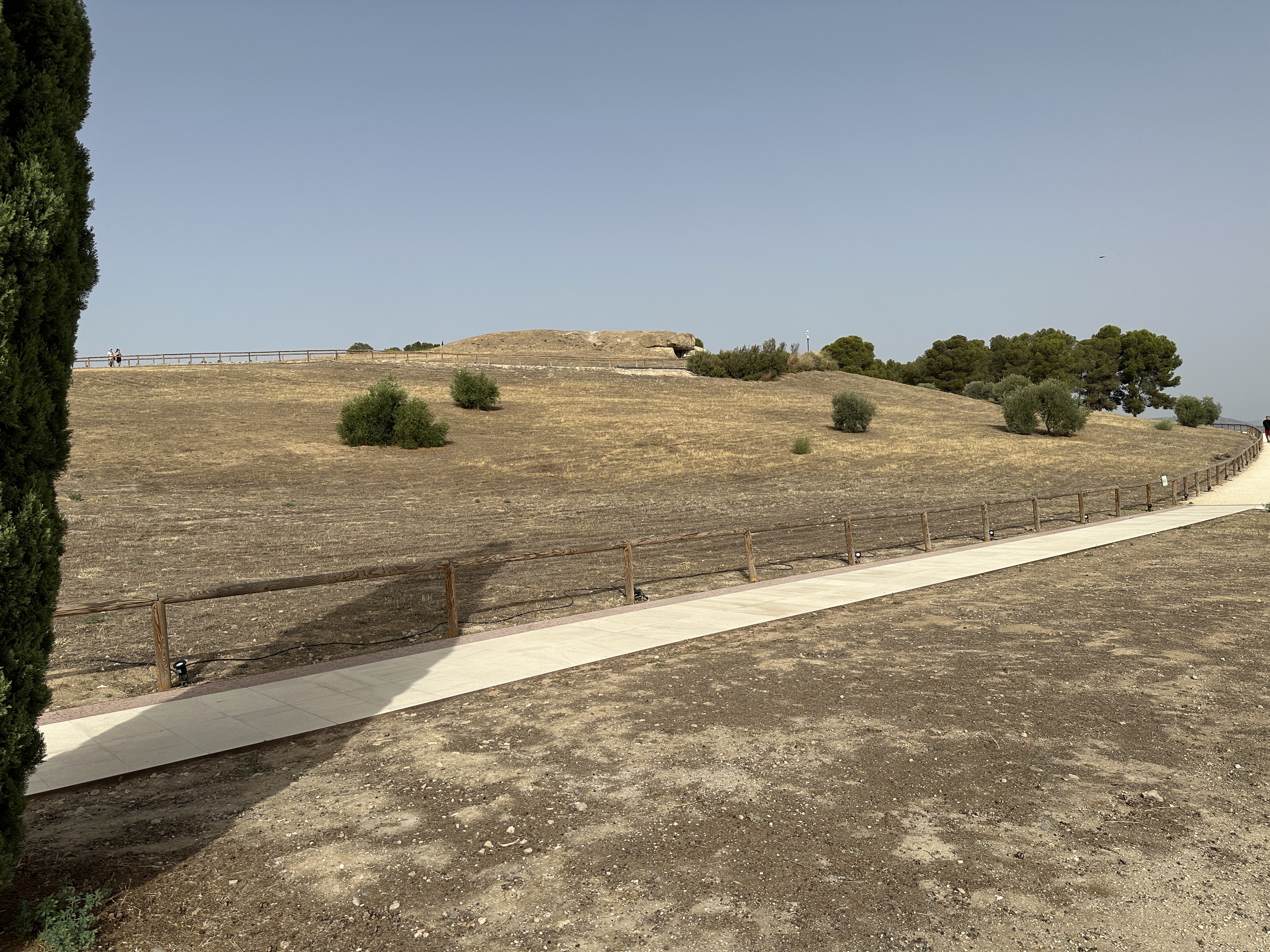 Dolmen van Antequerra: wit pad over droge weide en grafheuvel in de verte. 
