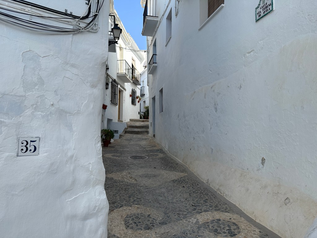 Heel smal steegje tussen witte huizen. 