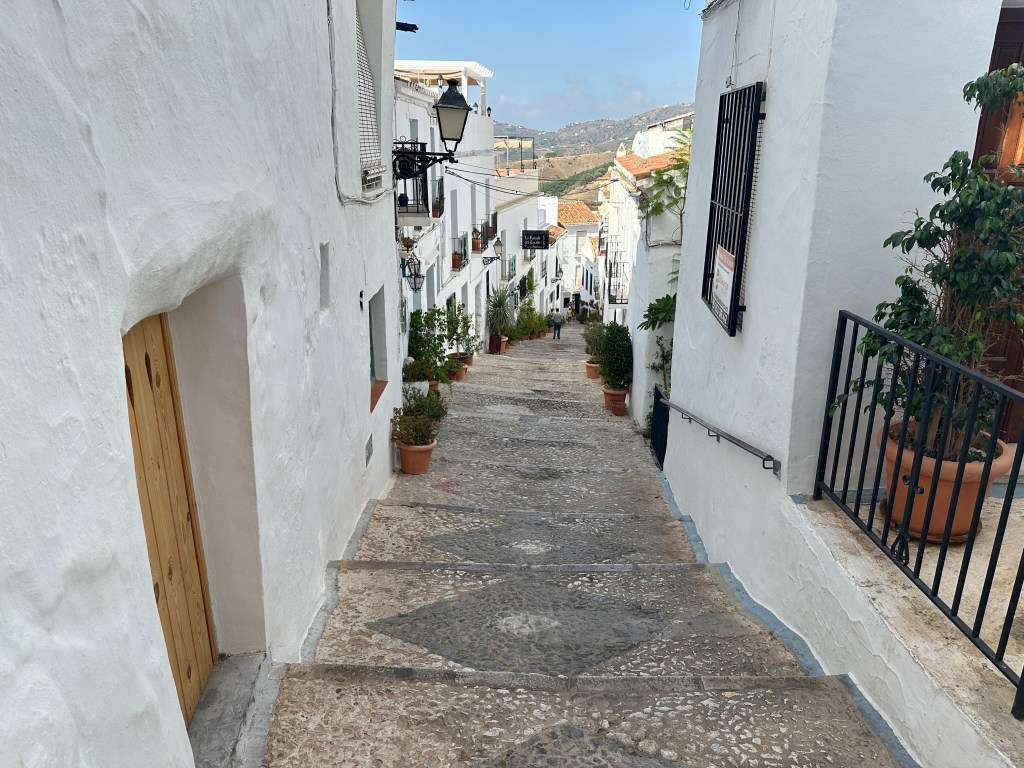 Dalend straatje met trappen tussen witte huizen. 