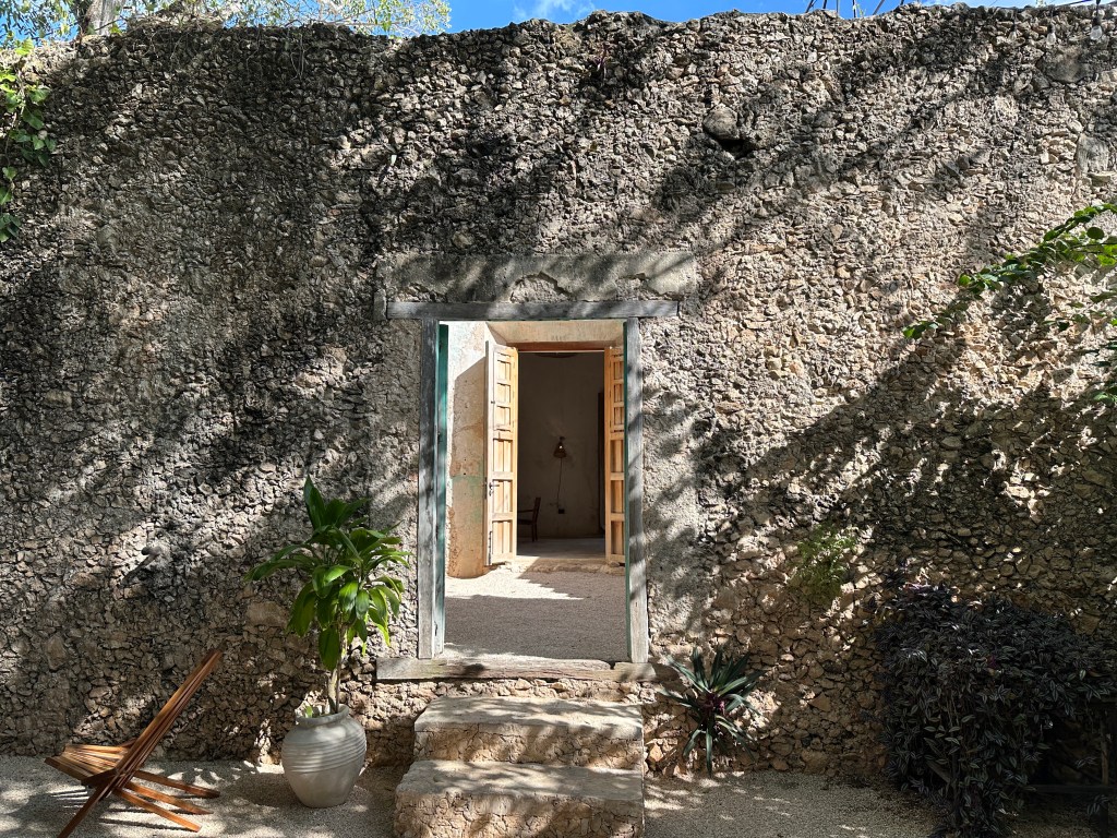 Muur van kleine gestapelde stenen met open deurgang. 