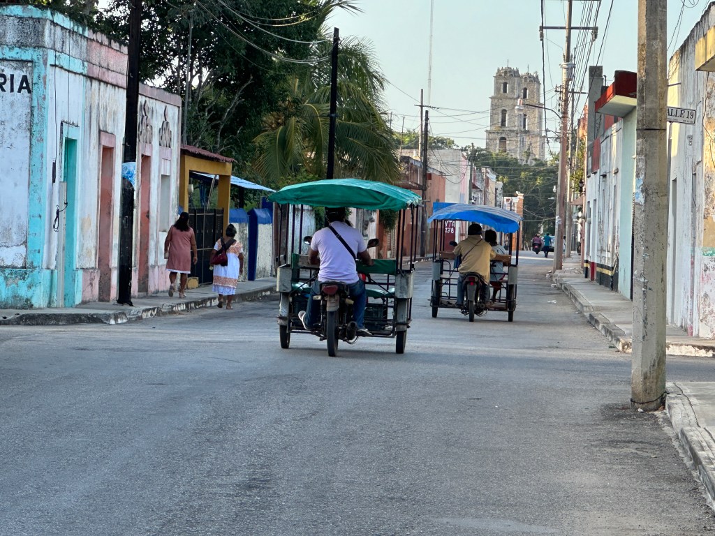 Twee driewielers in een lege straat op weg naar de kerk van Espita. 