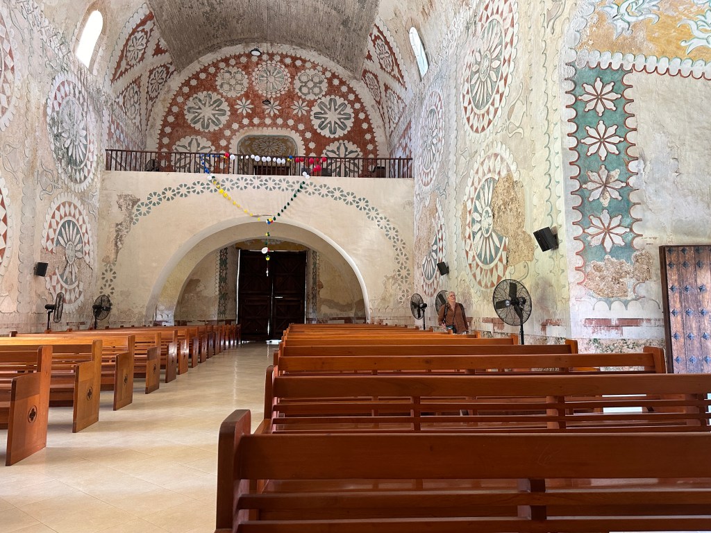 Binnen in de kerk: grote rosettas, houten banken. 