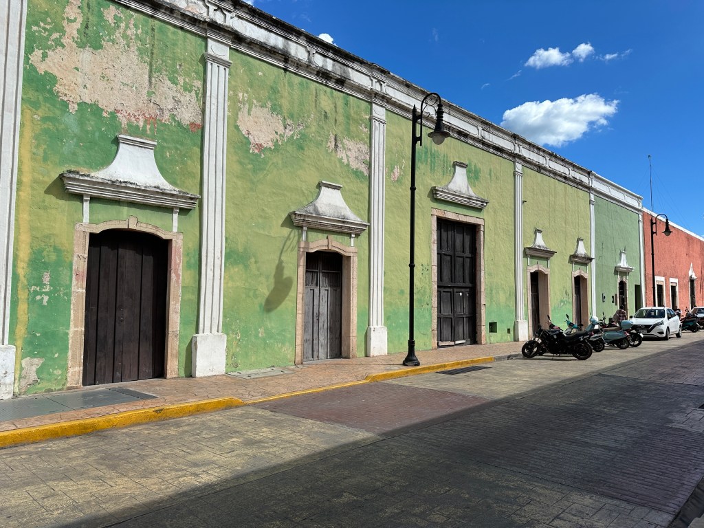Lang groen gebouw met afbladdeende verf. 