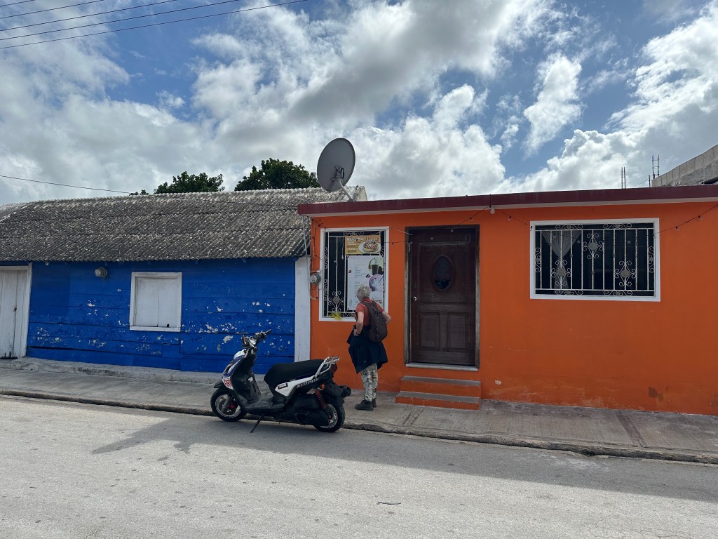 Donkerblauw huis naast bruinrrod huis en scooter in San Felipe. 