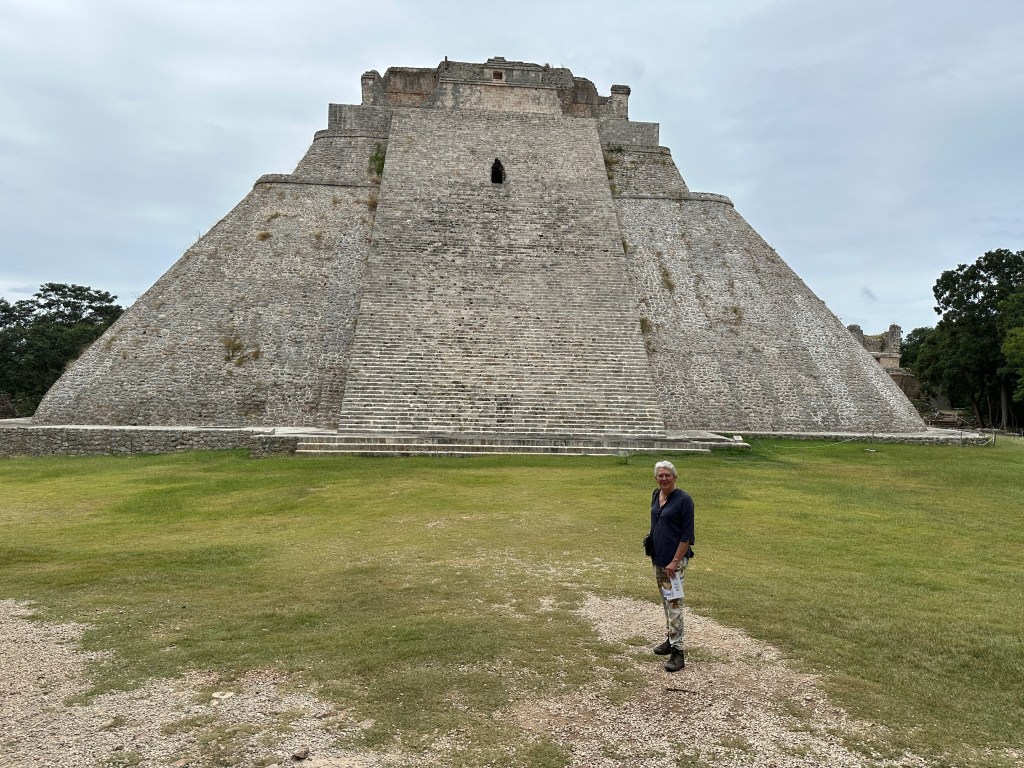 Grasveld met één toeriste en heel grote trap-piramide. 