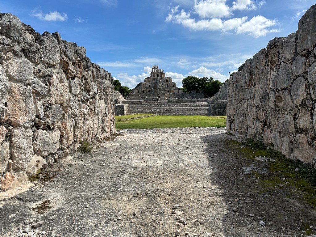 Muren aan weerskanten leiden naar piramide in achtergrond. 
