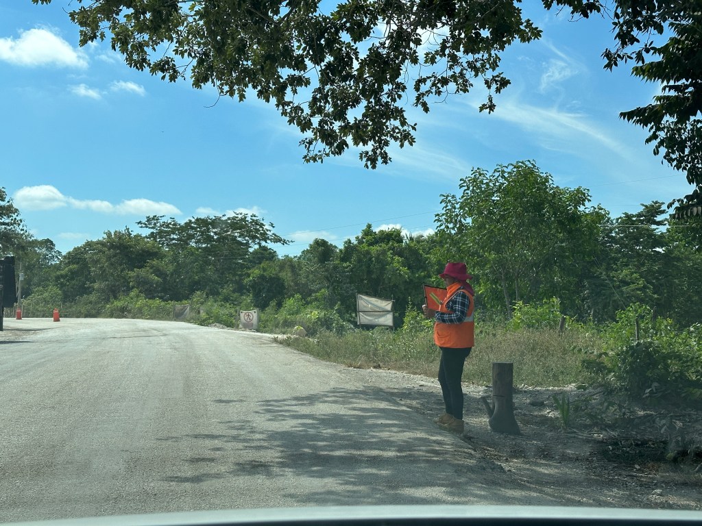 Wegenwerker met oranje fluo jas op route 186 in Yucatán