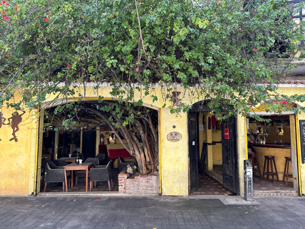 Geel klein restaurant met overhangend groen in Playa del Carmen