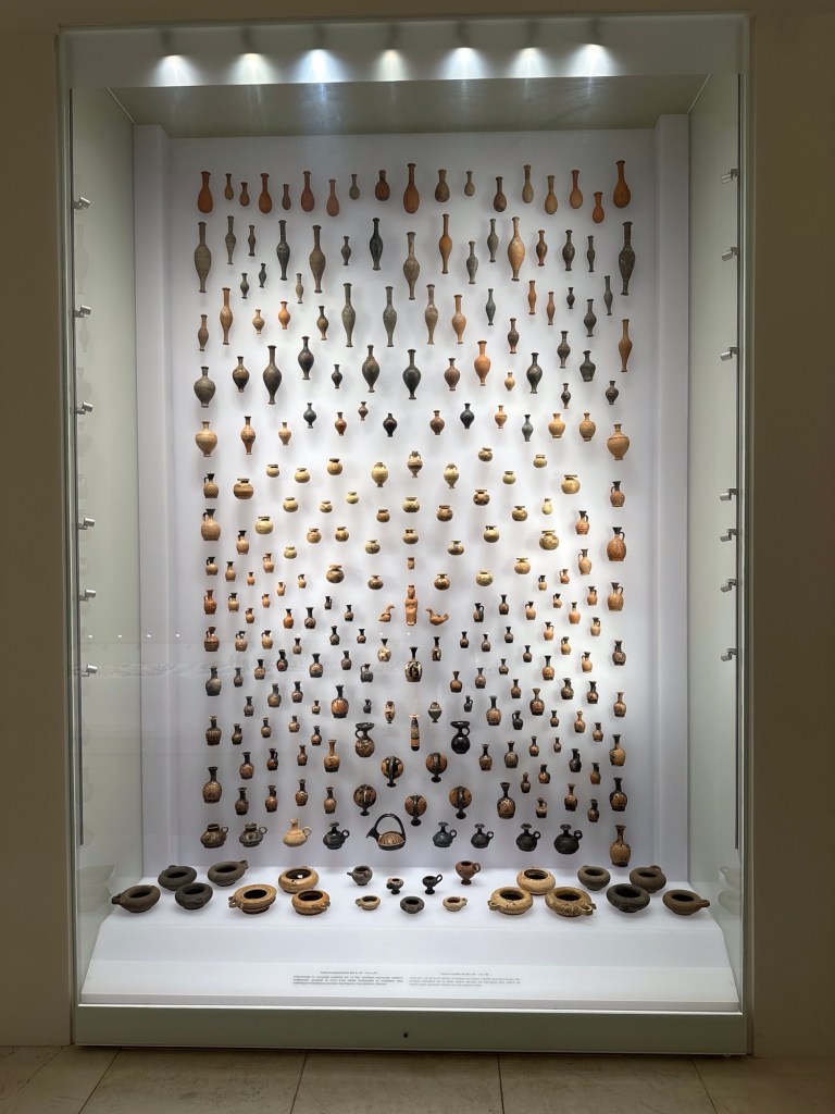 Polycentric museum Aigai: honderden kleine vaasjes op een verticale verlichte wand