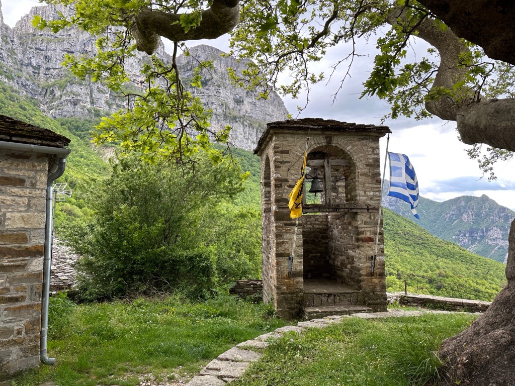 Papigko, Vikos: klokkentorentje met Griekse vlag voor grote rotsen