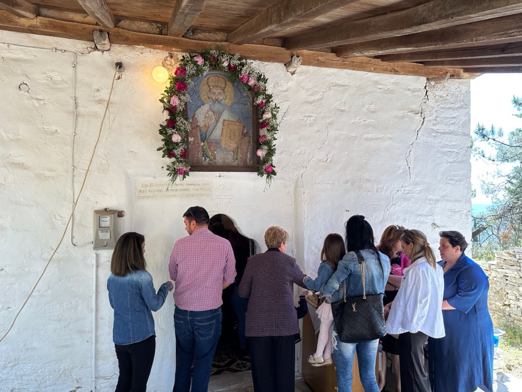 Gelovigen voor smalle ingang van wit kerkje in Pelion, Centraal Griekenland