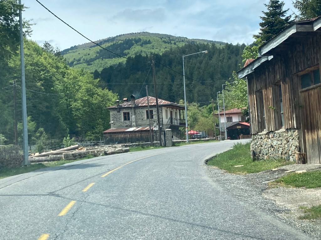 Bochtige bergweg met oud houten huis rechts in Milea, Centraal Griekenland
