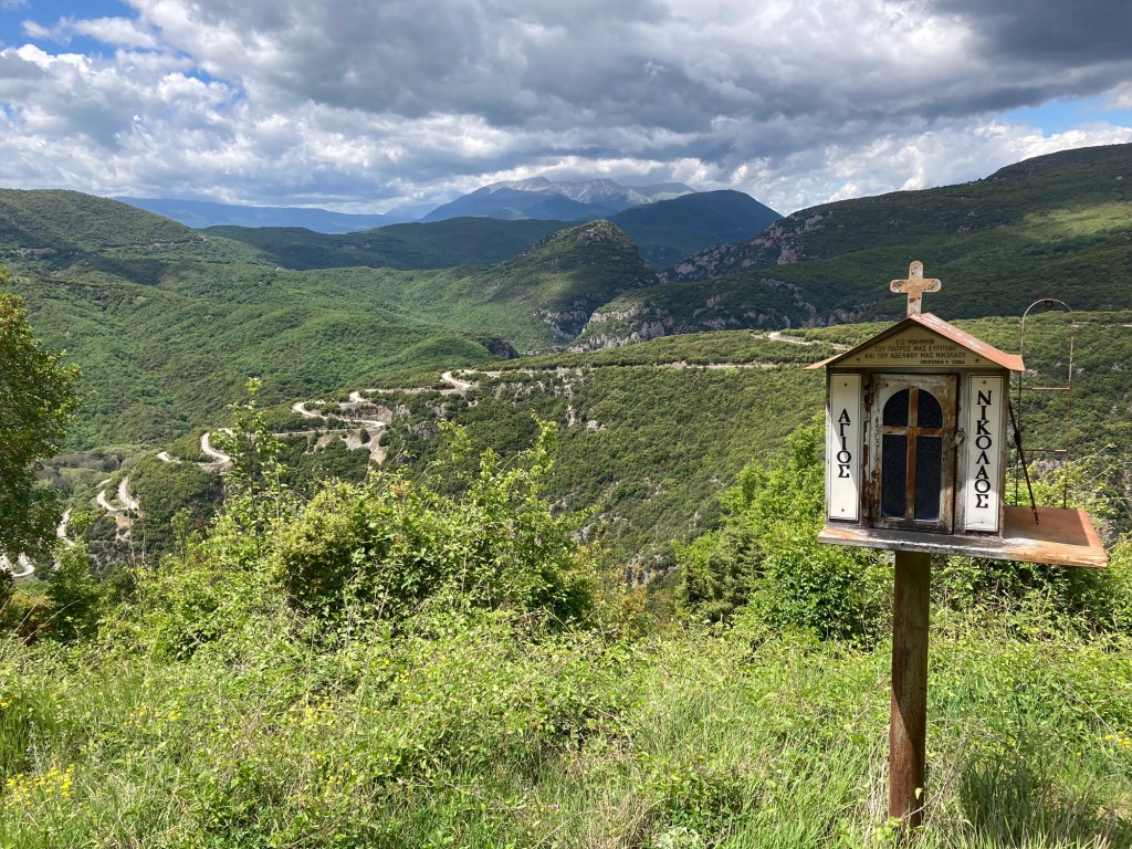 Papigko, Vikos: groen berglandschap met slingerende weg en kapelletje rechts