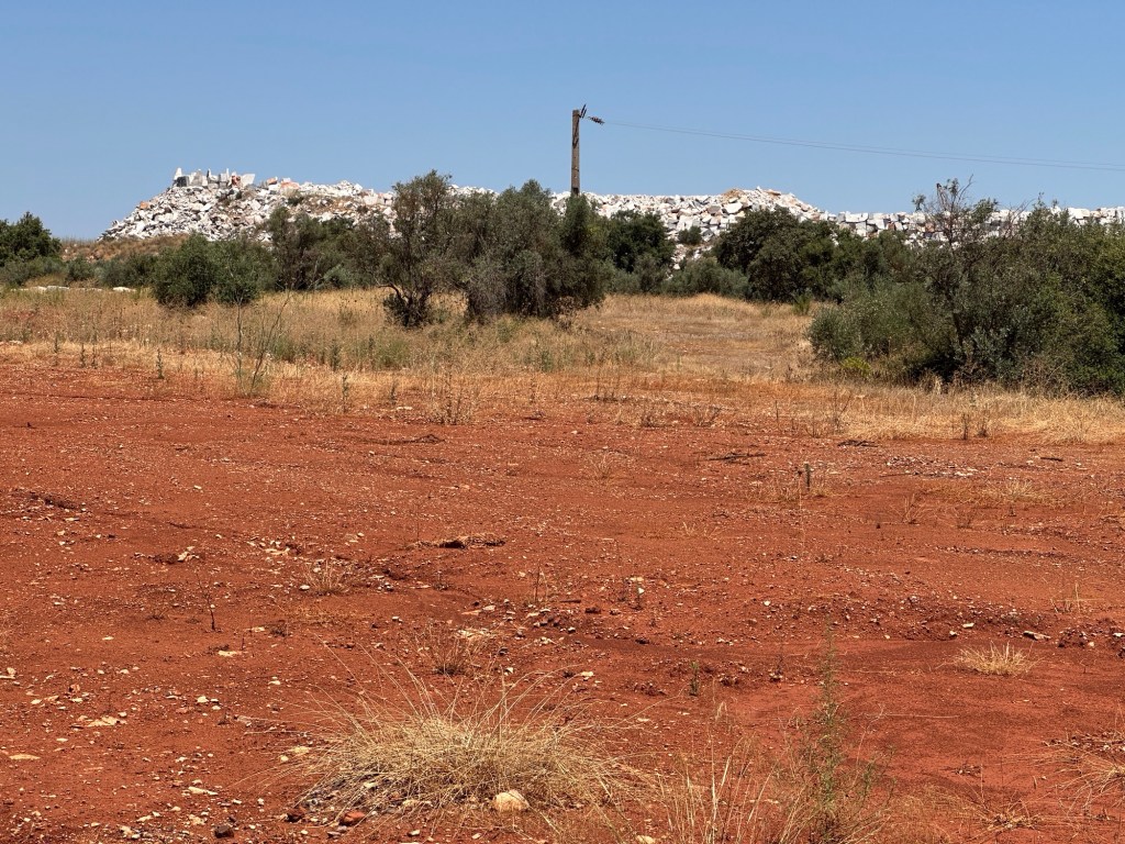 Marmergroeves, Vila Viçosa: berg van witte steen-afval voor plein met rode aarde