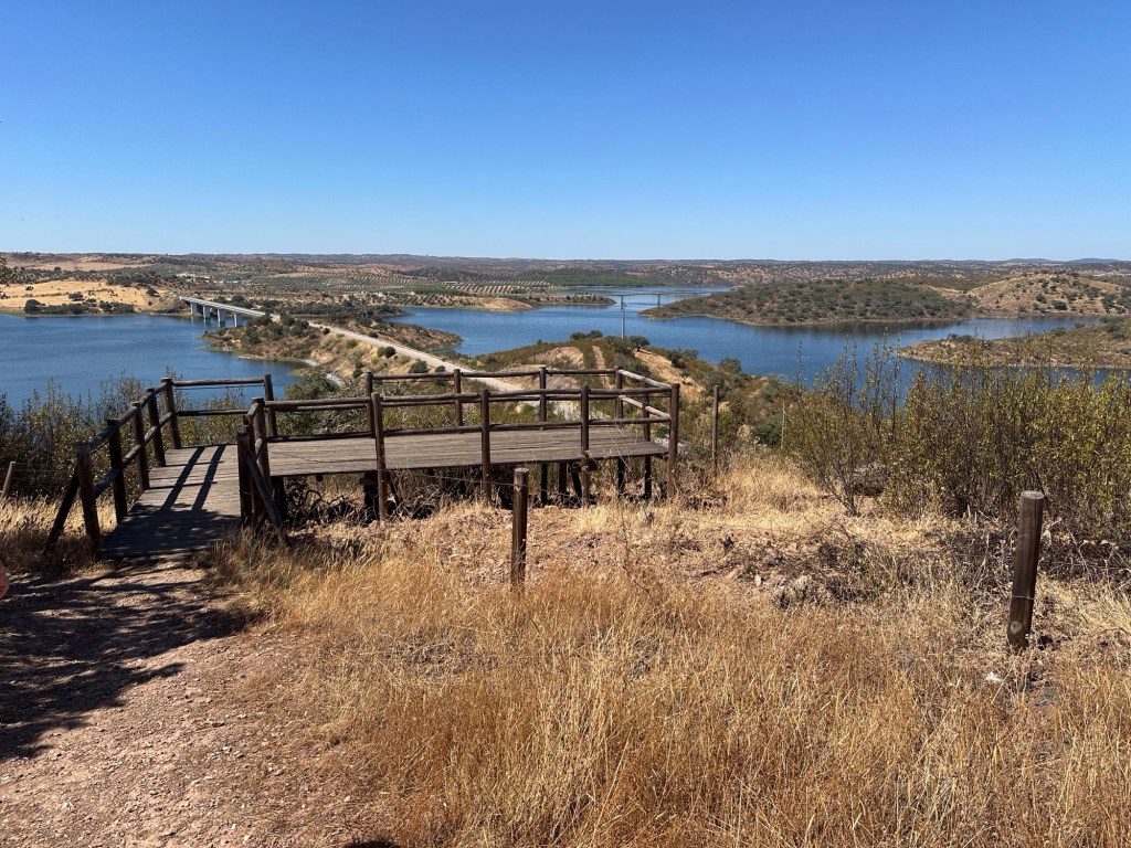 Houten platformen van Miradouro Alqueva met meer en brug over meer in de achtergrond