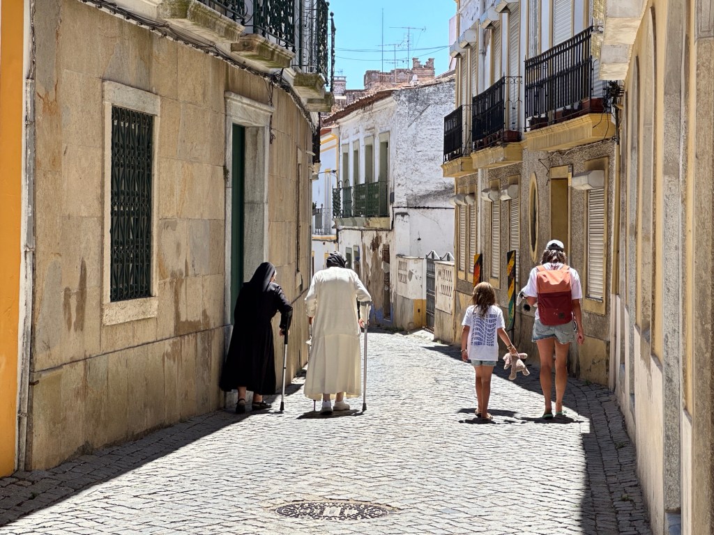 Smal, dalend straatje in Beja met nonnetje in zwart en nonnetje in wit, beiden met krukken