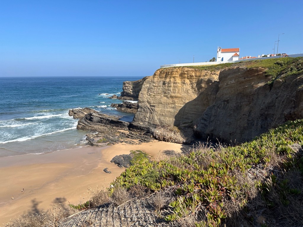 Rotsen met wit kerkje aan de oceaan in Zambujeira