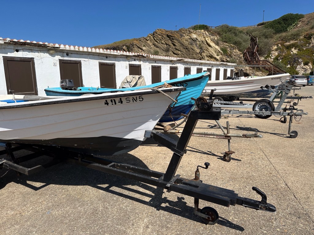 Boten op het droge voor lang, wit gebouw in Porto Covo