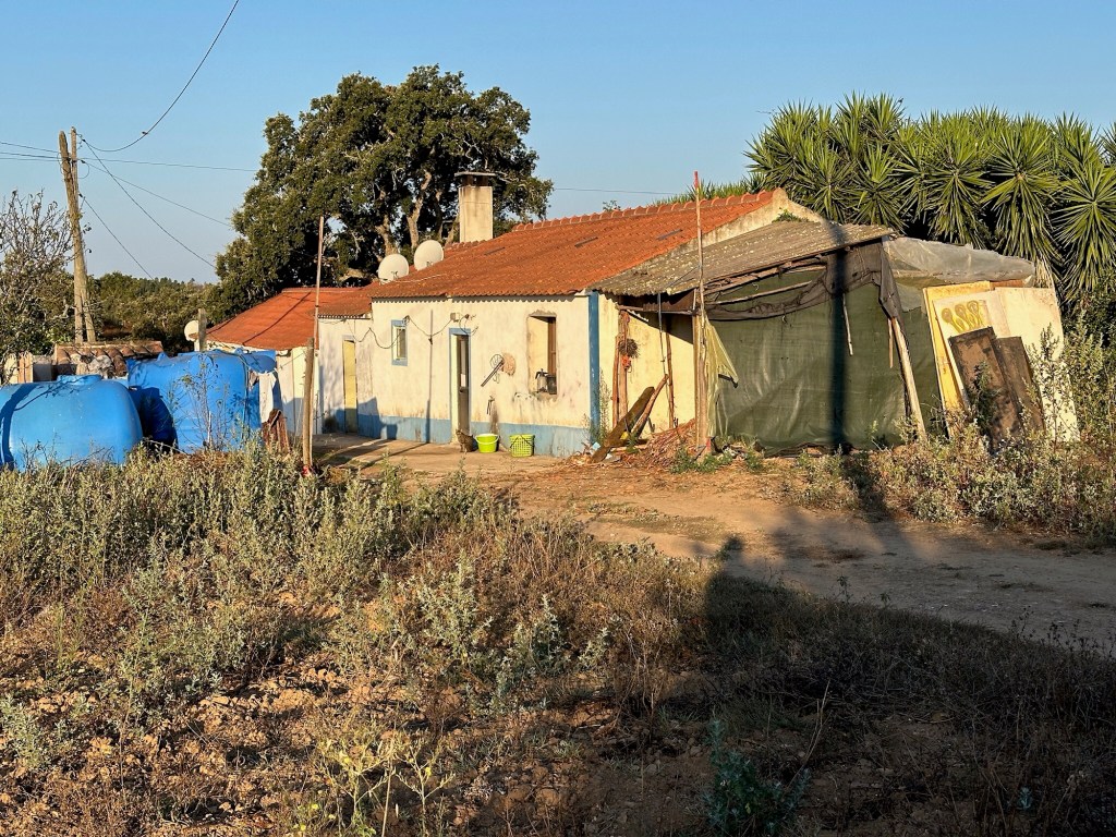 Armoedig huis met rood dak en veel rommel in Algares
