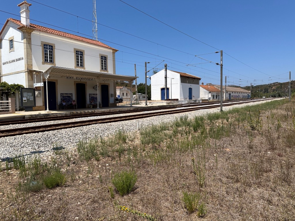 Wit stationsgebouw en andere witte gebouwtjes met spoorlijn in  Santa Clara-Sabóia