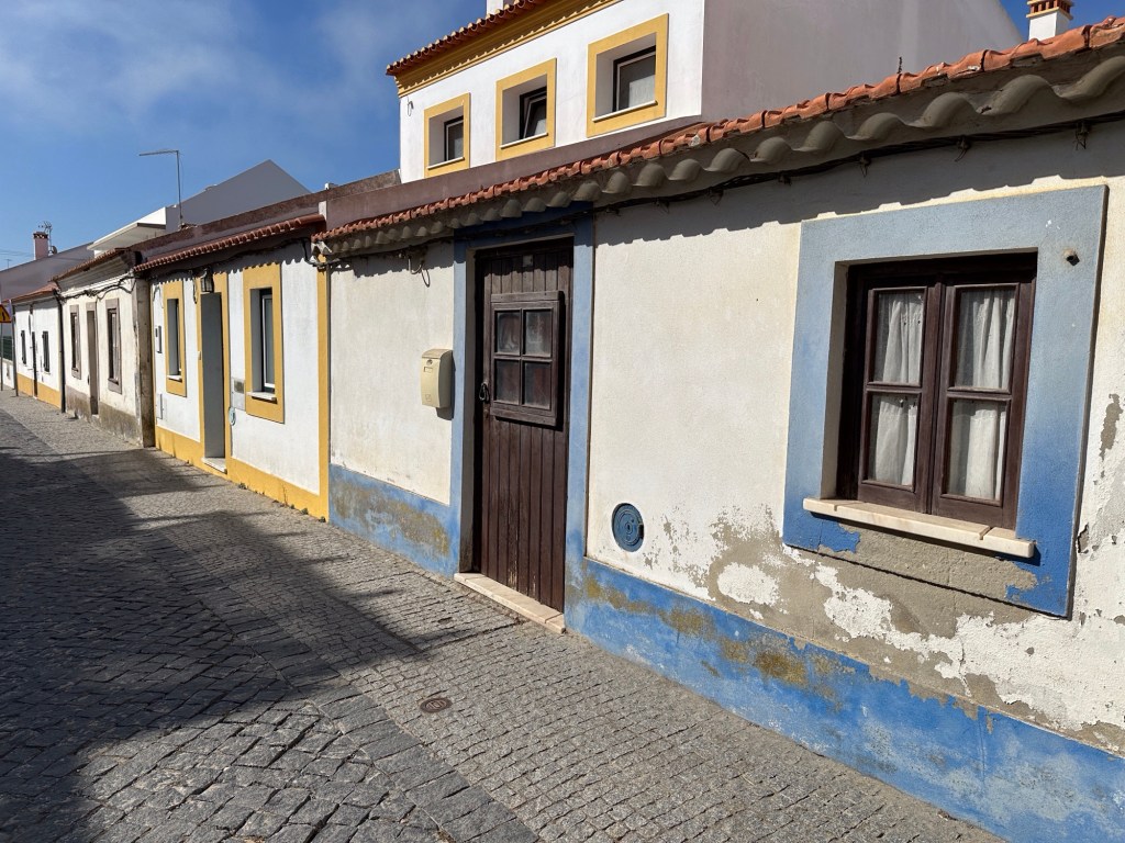Straatje met witte huisjes met gekleurde deur- en vensterranden in Villanova de Milfontes