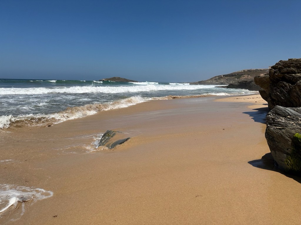 Maagdelijk strand met roodbruin zand in Porto Covo