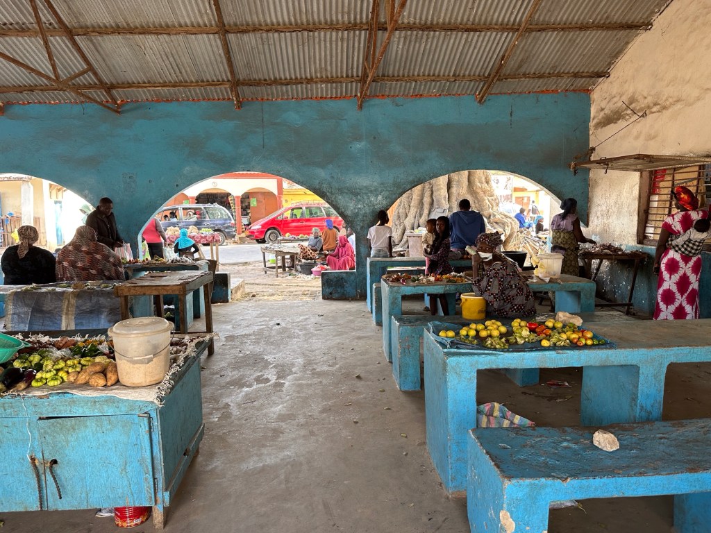 Binnenzicht Kartong markt met blauwe betonnen toonbanken en uitgestalde groenten en fruit