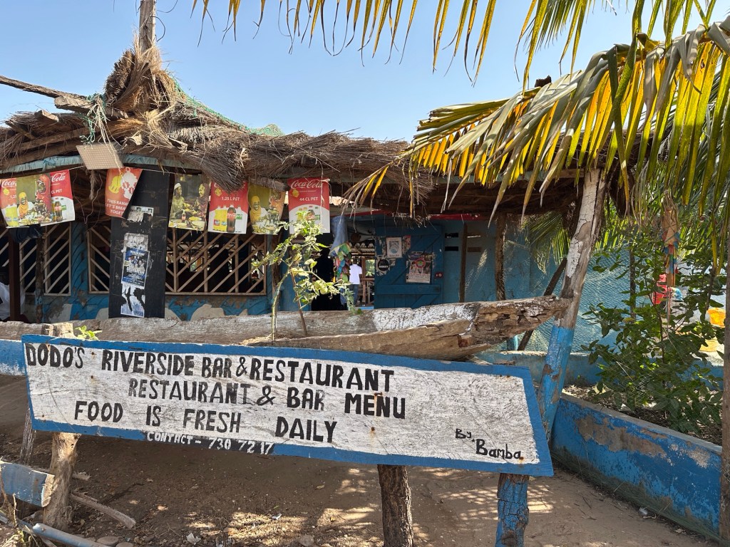 Oud welkomstbord van Dodou’s restaurant met bar onder palmdak