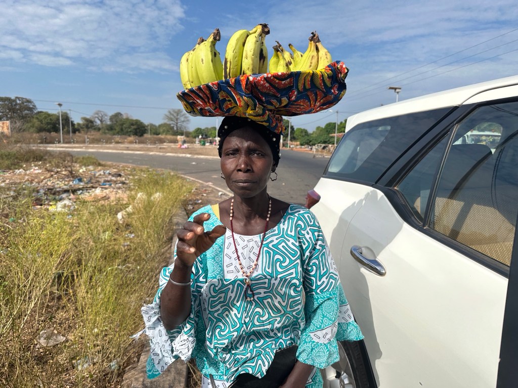 Zambiaanse in licht-blauw kleed met mand bananen op het hoofd