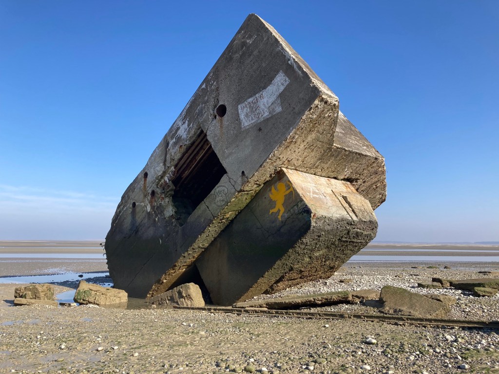 Gekantelde bunker op strand bij eb