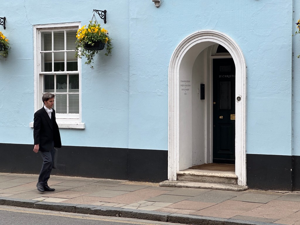 Lichtblauw gebouw met Eton student in zwart uniform