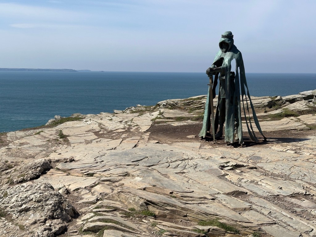 Koning Arthur beeld in Tintagel Castle met zee op achtergrond