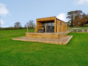 Houten container, uitkijkend huis op grasveld