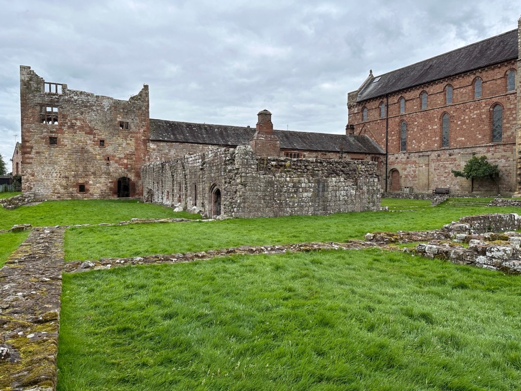 Grasveld met ruïnes op achtergrond. 