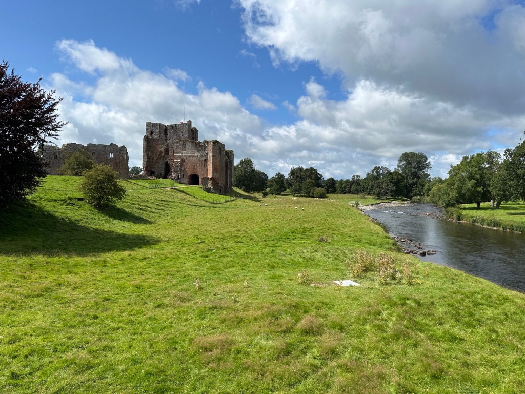 Rivier, grasveld, kasteelruïne. 