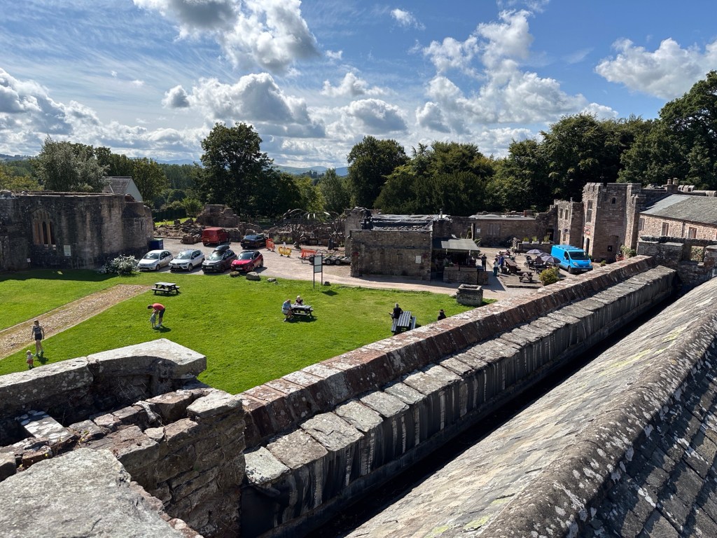 Kasteelmuren, gebouwen en groen binnenplein. 