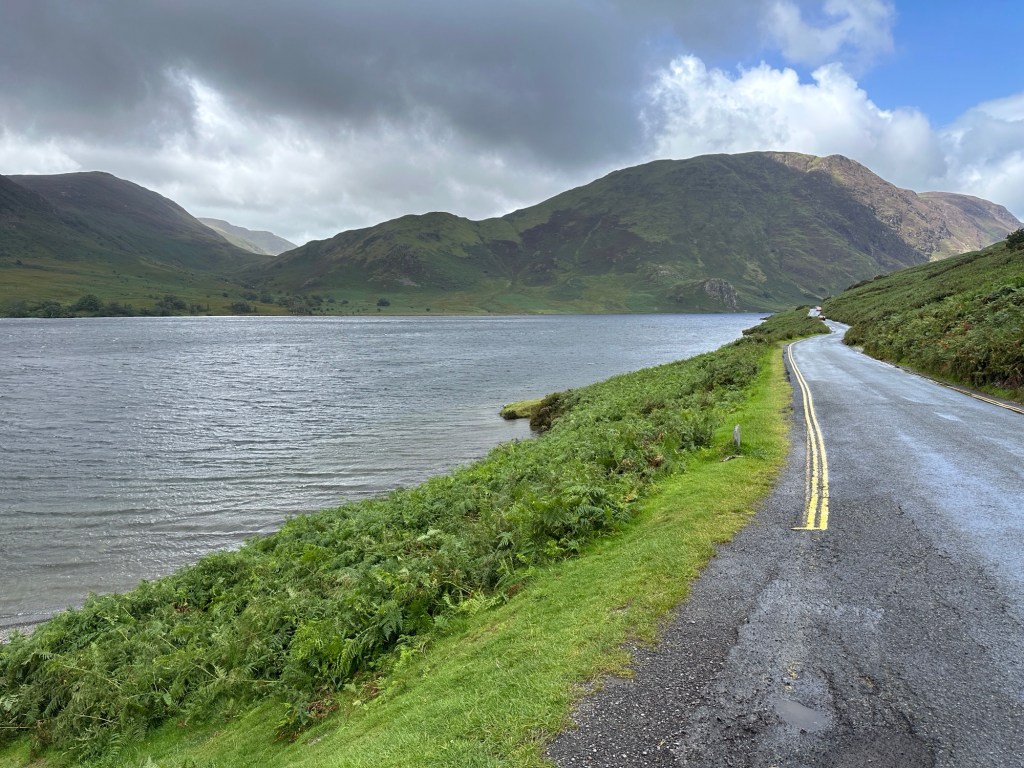 Asfaltweg langs meer met bergen.