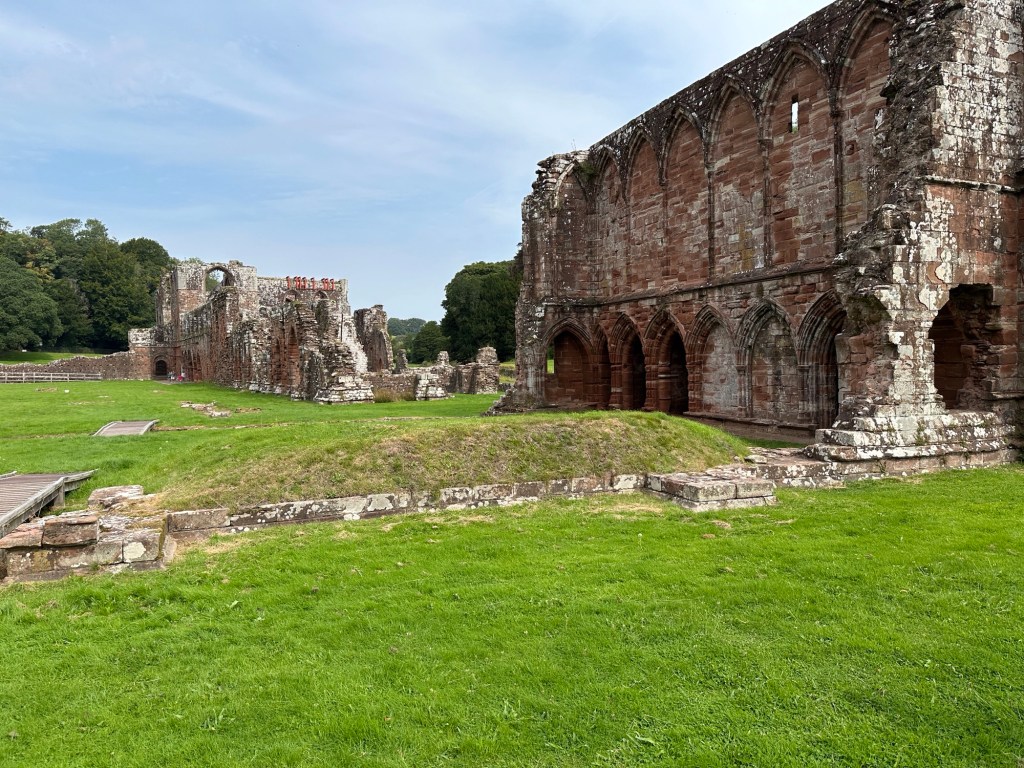 Grote ruïne op grasveld. 