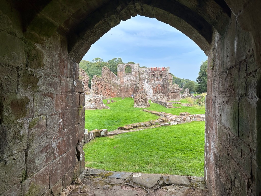 Zicht op ruïne in de zon vanuit kloosterraam. 