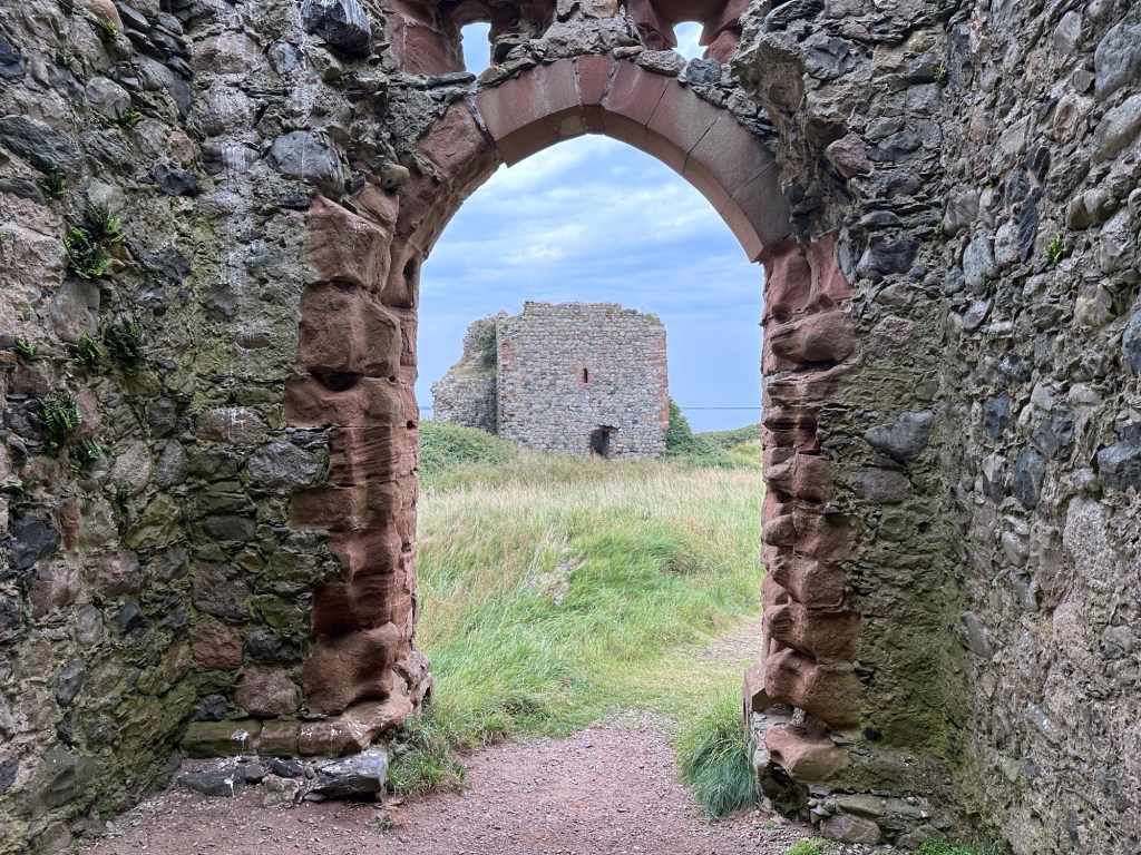 Ruïne in de zon vanaf boogvormige toegangspoort tot kasteel. 