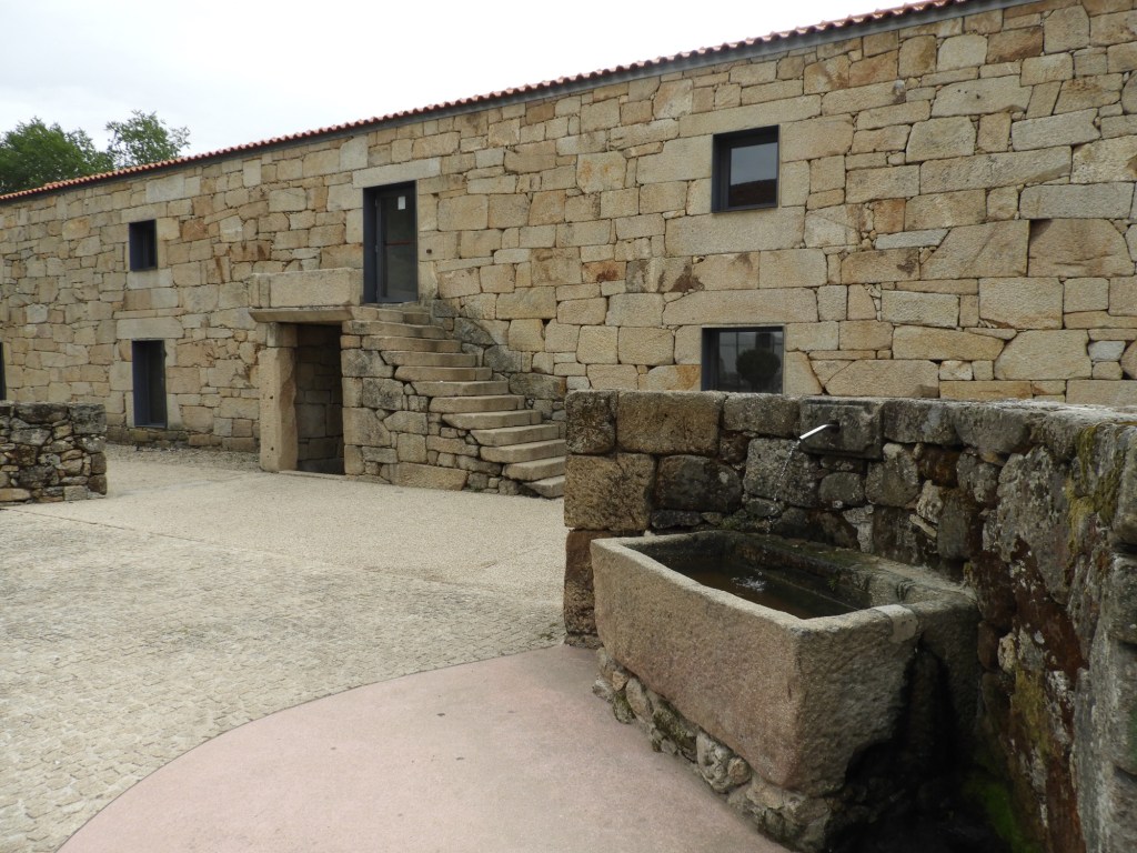 Beige museumgebouw met trap en stenen drinkbak.
