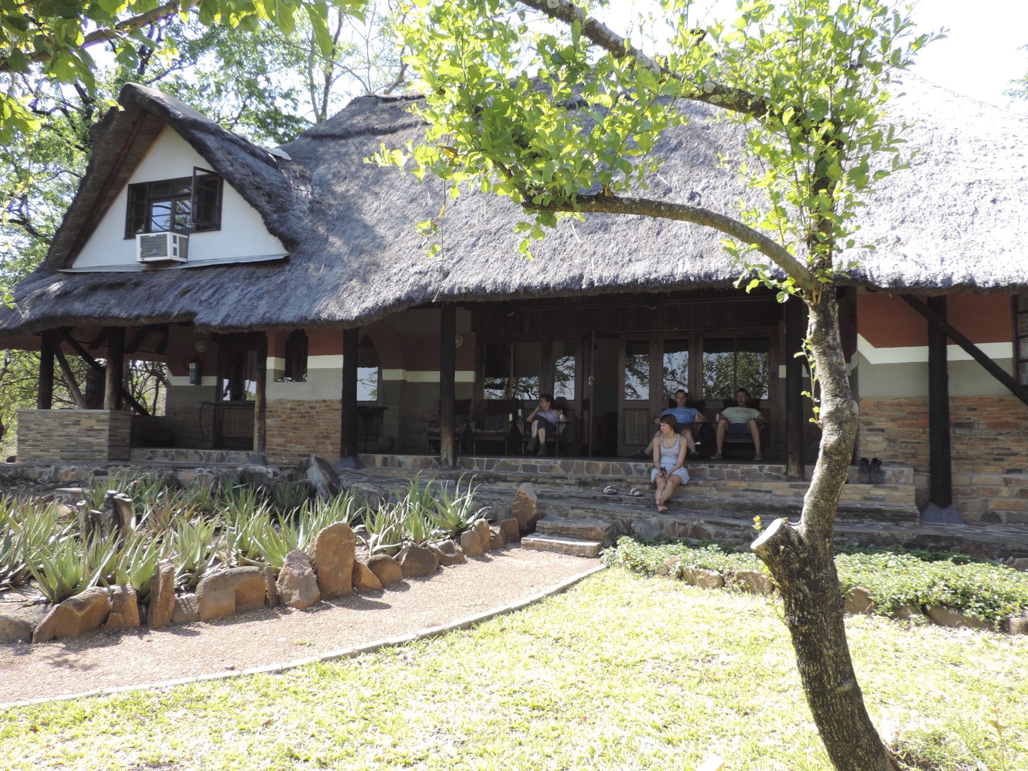 Groot gebouw met rieten dak en terras.