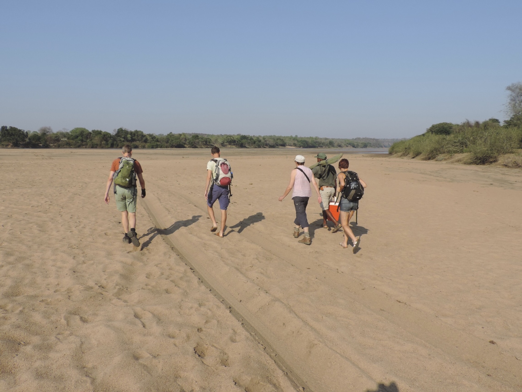 Toeristen op grote zandvlakte van rivier.